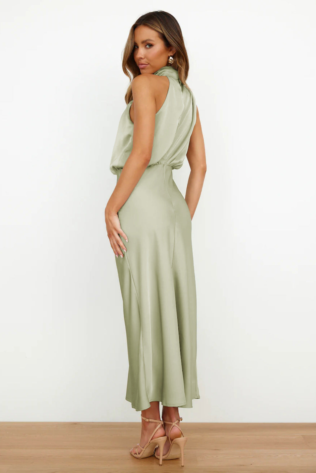  Female model showcasing an elegant long dress with a graceful silhouette on a plain background.