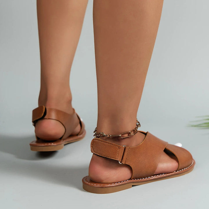 Woman posing back angle showcasing sandals plain background fashion studio setup