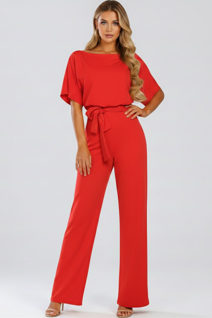 Woman wearing a full-body jumpsuit with loose sleeves and long open-leg shape on a plain background.