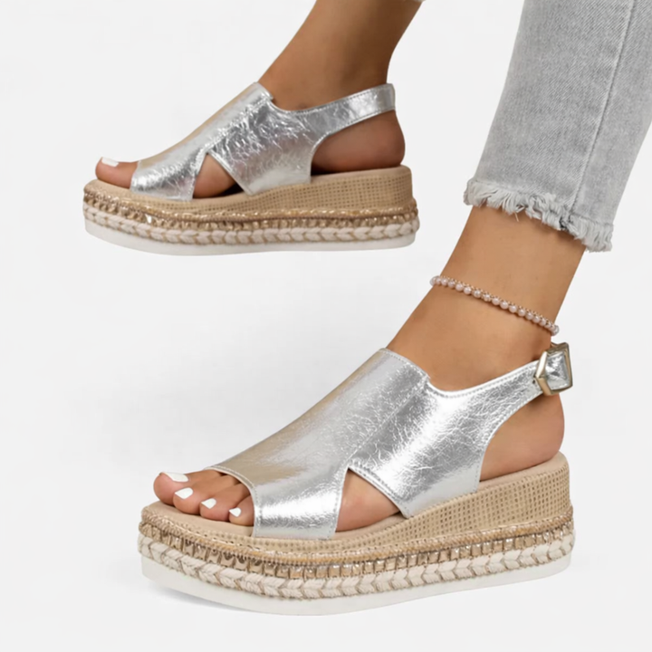 Woman model showcasing slingback wedge sandals with side cut-out details on a plain background.