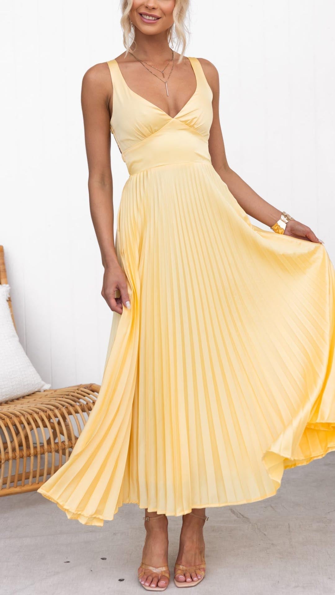 Woman wearing a pleated V-neck dress on a plain background.