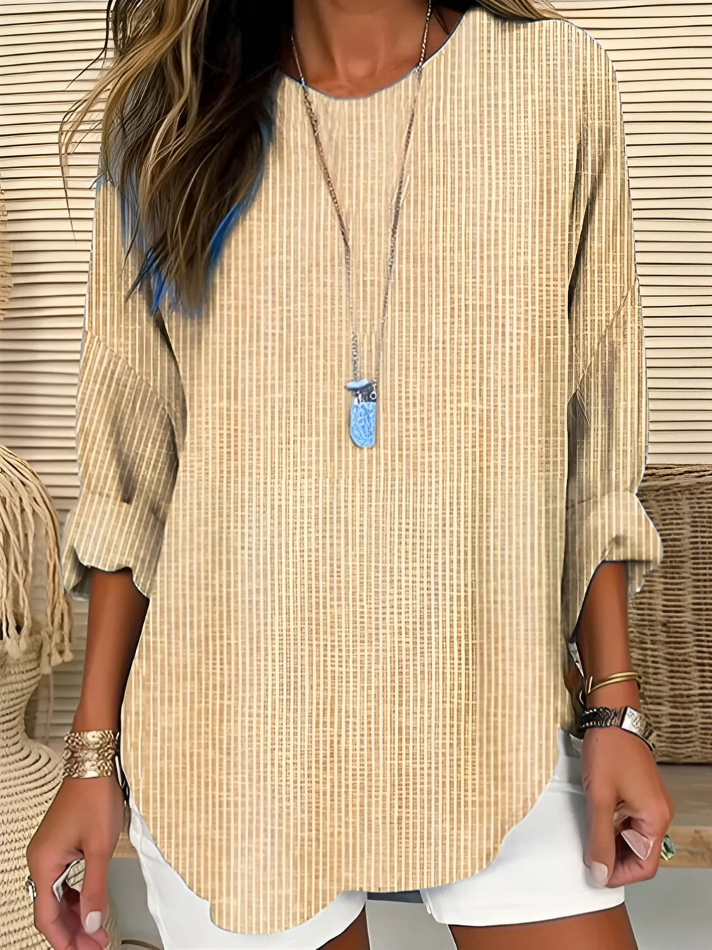 Woman modeling a relaxed striped blouse with crew neckline on a clean background.