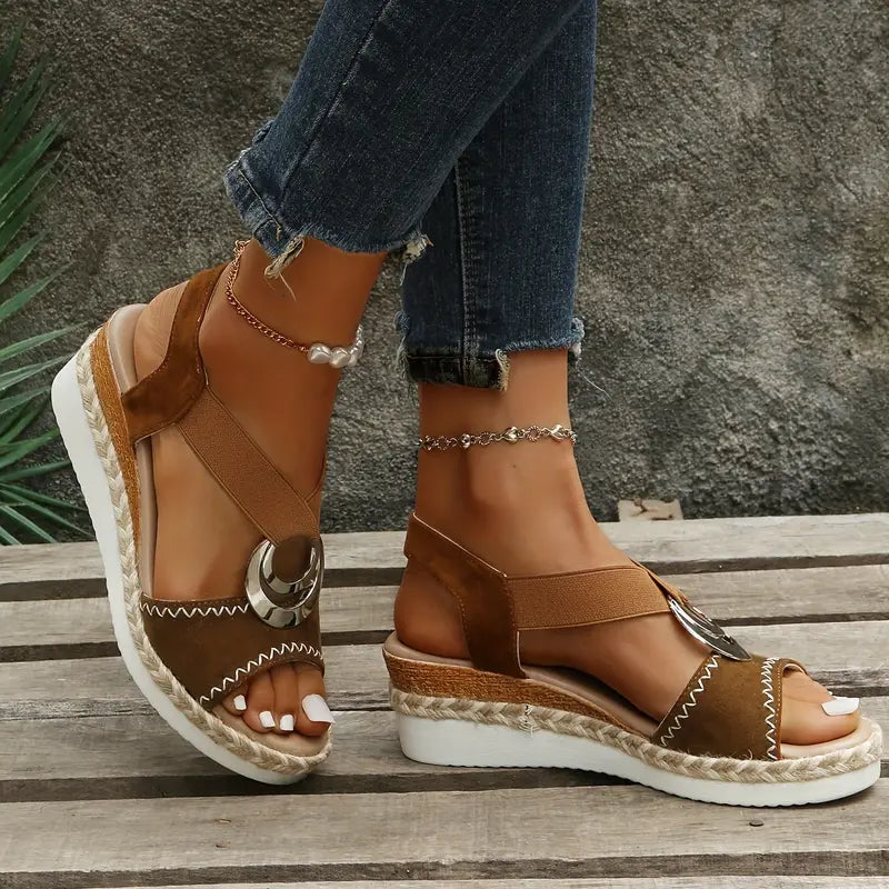 Top angle of fashionable wedge sandal worn on foot, plain background.