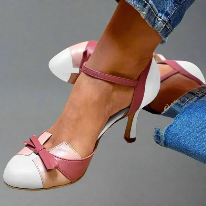 Woman posing in chic pumps with side profile plain background.