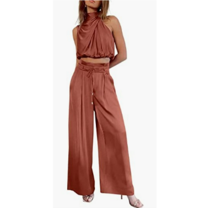 Woman showcasing a sleek sleeveless top paired with flowing pants on a plain background.