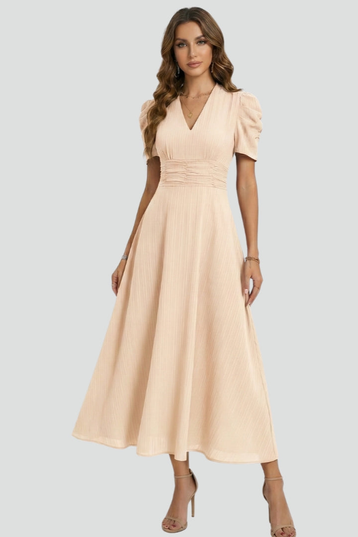 Female model wearing flowing dress from front view, gray background.