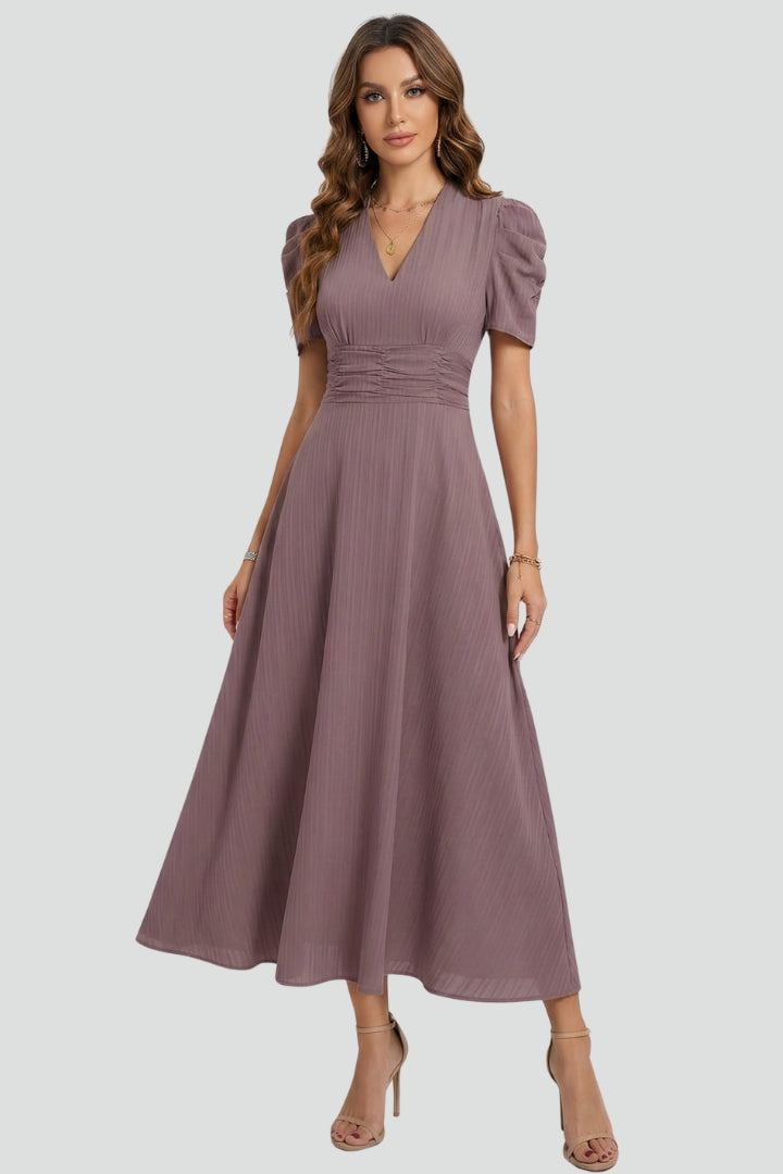 Woman wearing flowy midi dress front view on plain gray background.