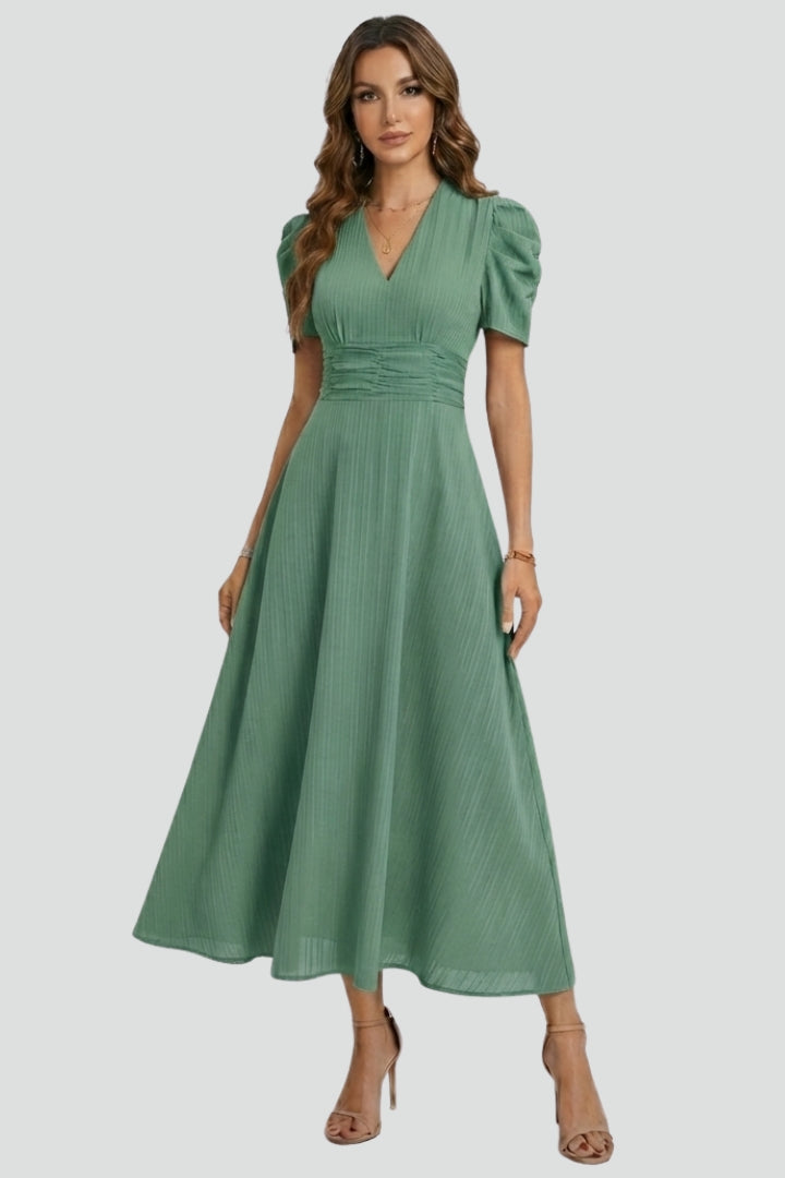 Female model showing full-length outfit on plain gray background indoors.