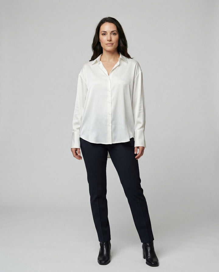 Woman showcasing an elegant silk blouse with a classic tailored design against a plain background.