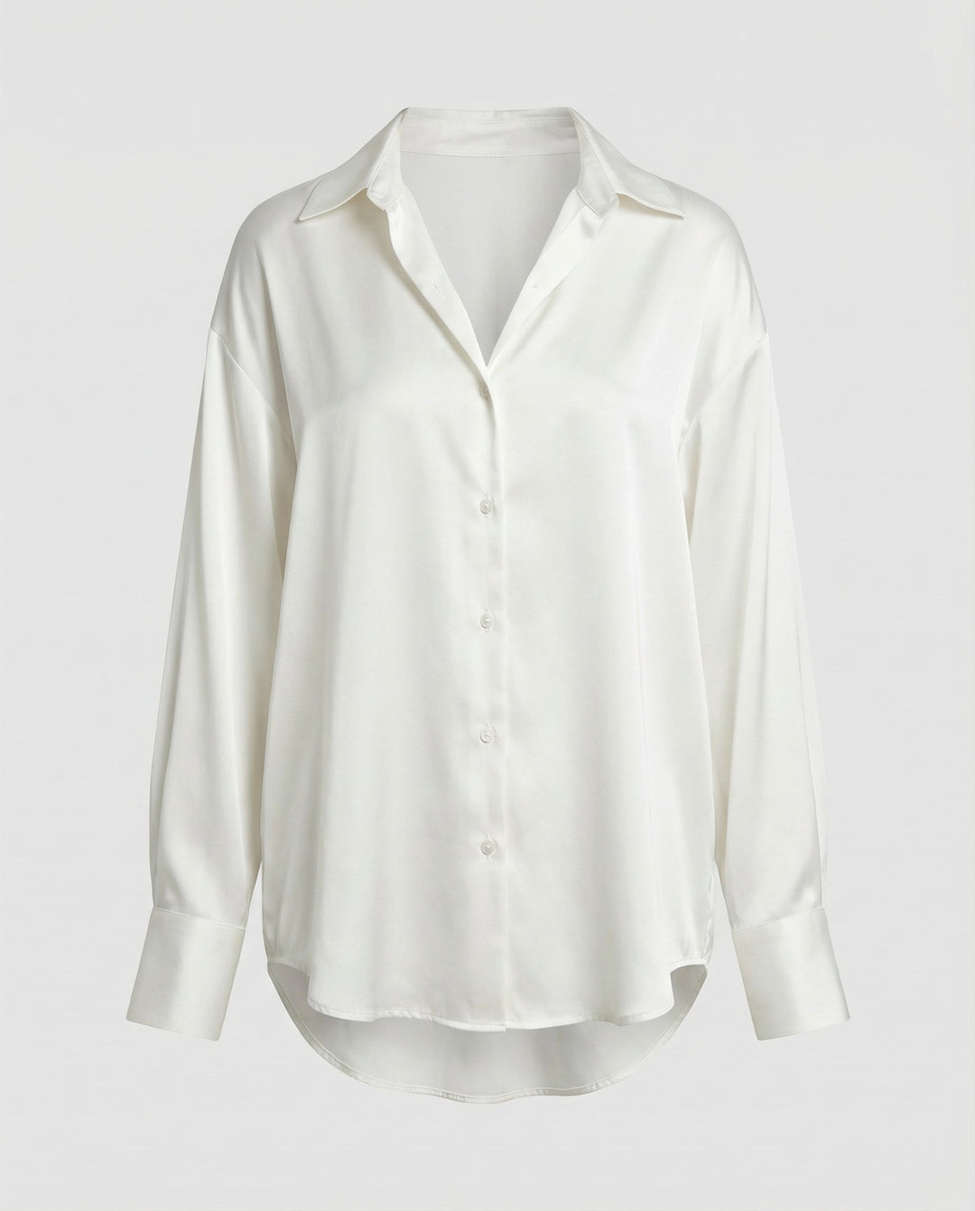 Woman wearing a button-front silk blouse with long sleeves on a plain backdrop.