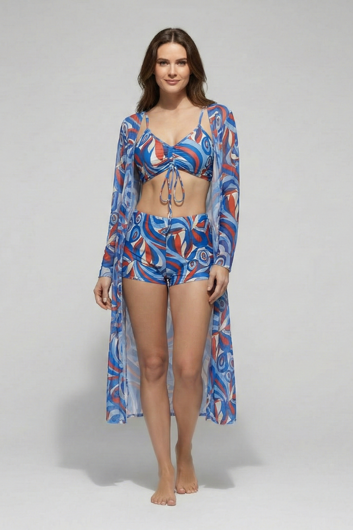 
Female model wearing a coordinated printed beachwear set with a bikini and long-sleeve layer on a plain background.