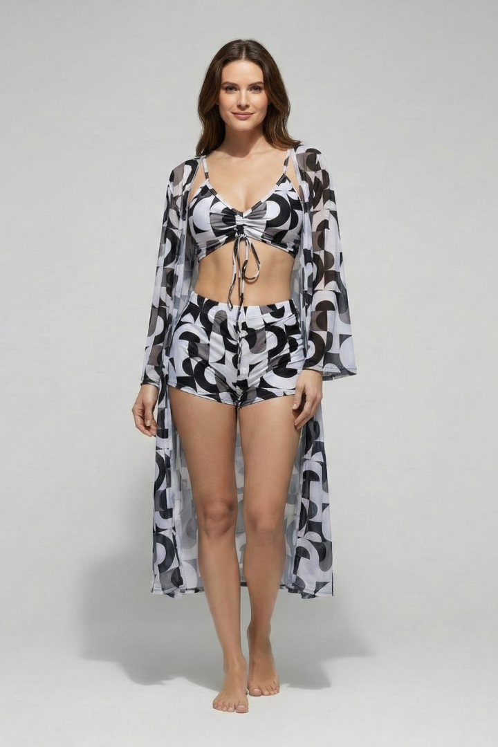 
Woman wearing a printed bikini set with thin shoulder straps and a matching long-sleeve cover-up on a plain background