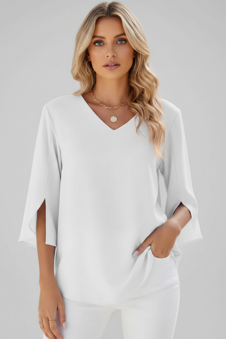 Polished woman on white top and white pants with left hand on the pocket front angle white backdrop