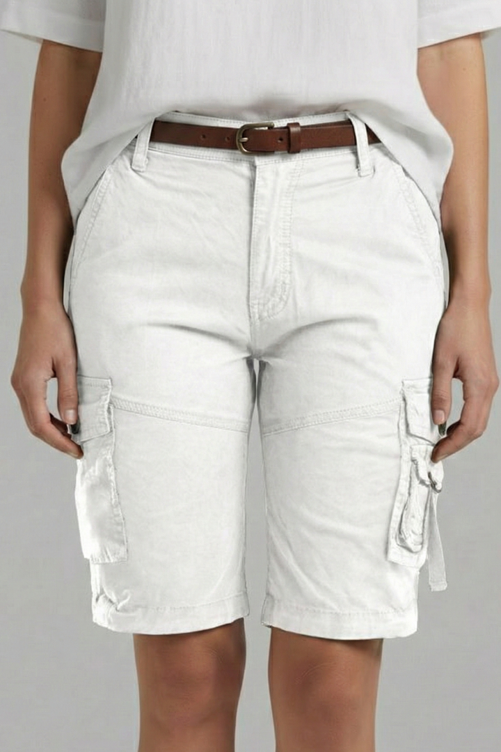 Female model posing in straight-leg white shorts gray background