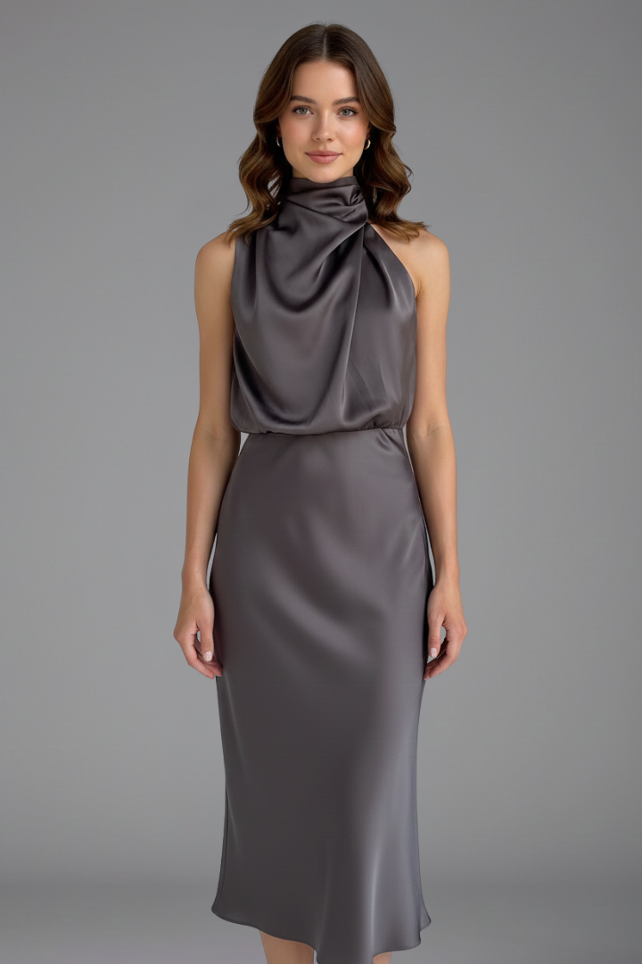 Female model showing full length dress on plain gray background.