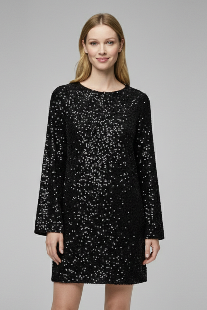 Female model standing in textured sequin dress on gray background.