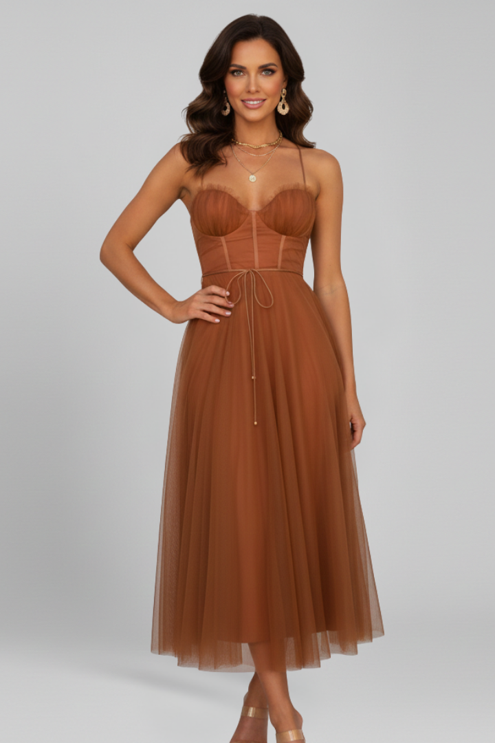 Woman with dangling earrings wearing strapless evening dress full body gray background