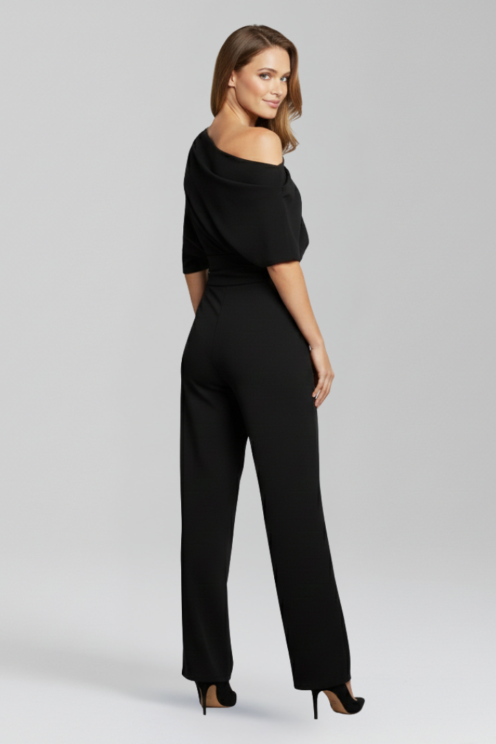 Woman in a long sleeve wide leg jumpsuit with a defined waist seam on a plain background.