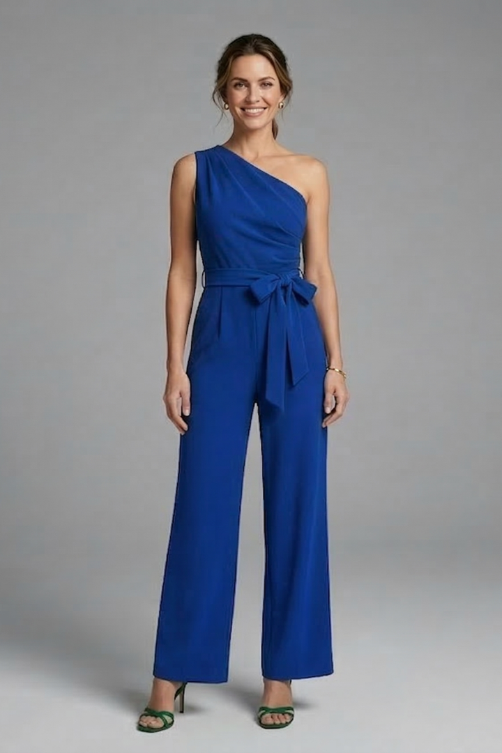 Female model wearing a clean sleeveless jumpsuit with uneven neckline shape on a plain background.