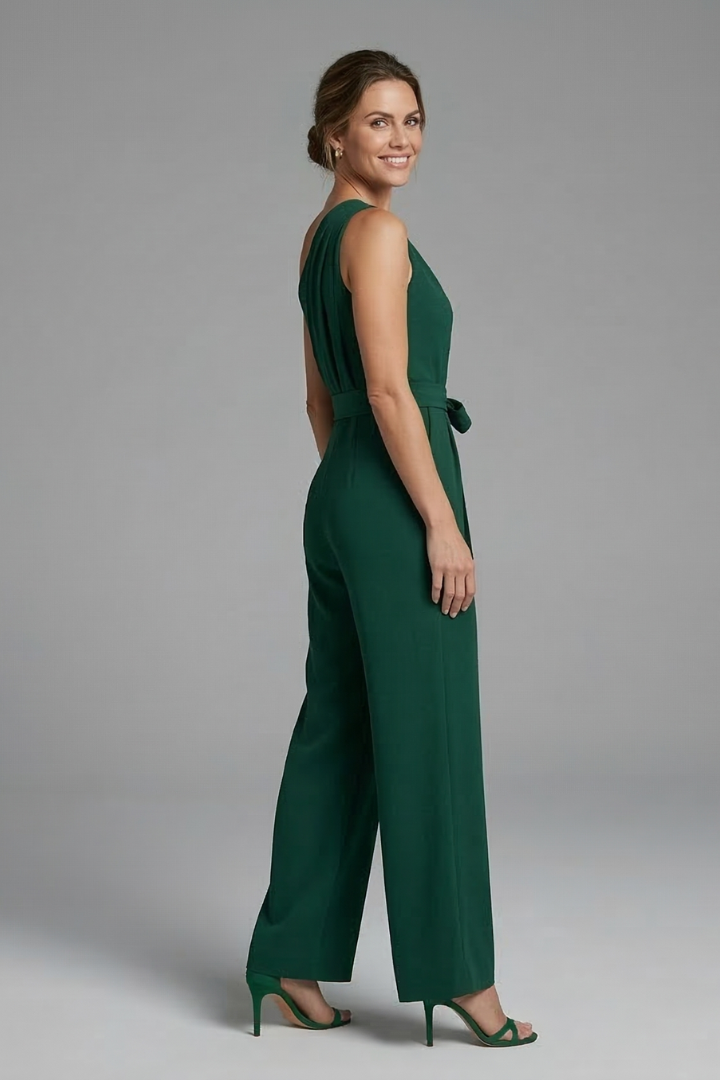 Female model in a plain woven jumpsuit with wide legs and attached belt on a plain background.