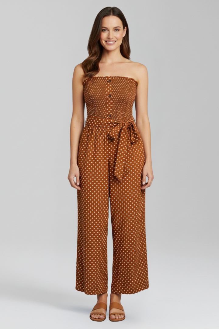 Woman wearing a strapless wide leg jumpsuit with button front on a plain background.