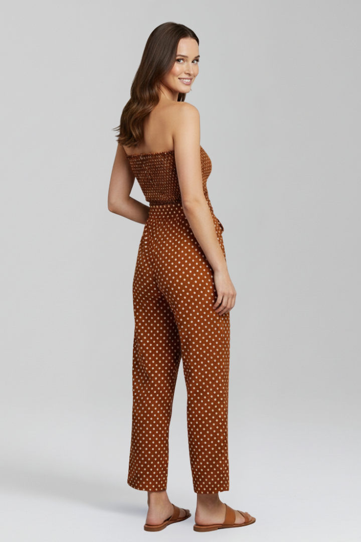 Woman styled in a strapless textured jumpsuit with wide legs on a plain background.