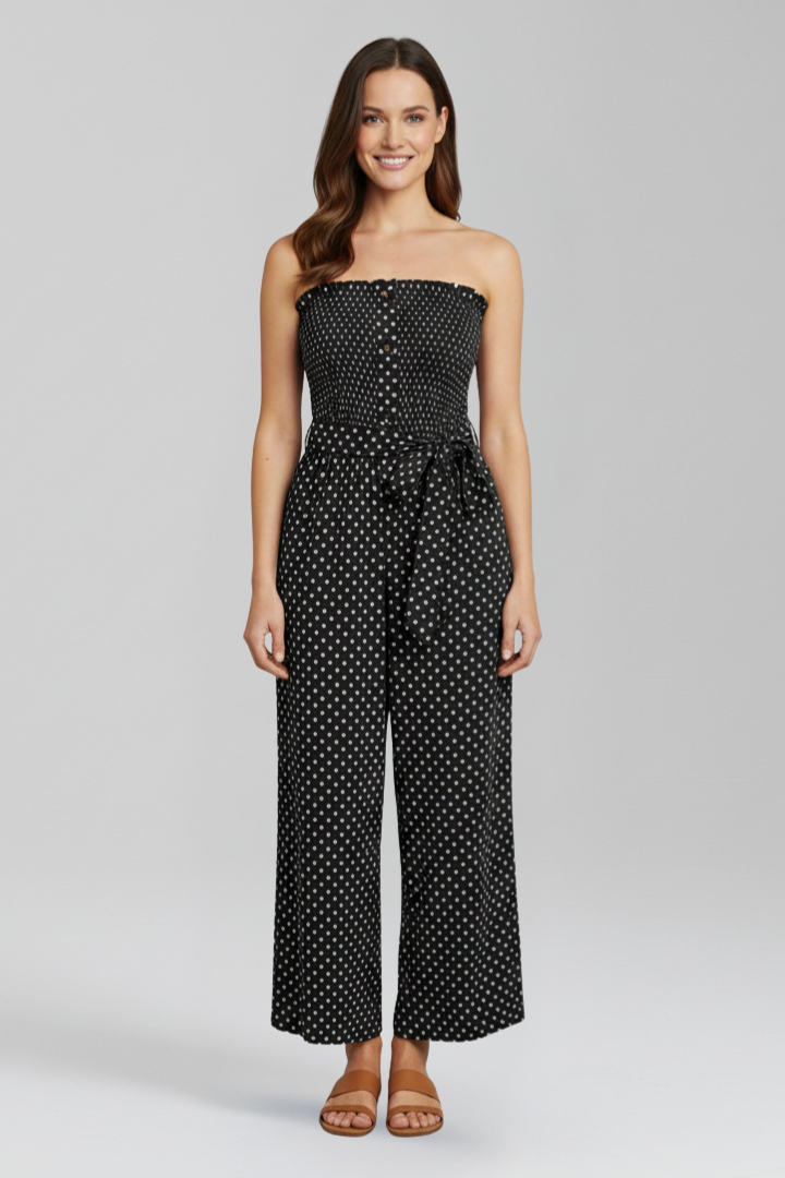 Female model in a wide leg strapless jumpsuit with dotted texture on a plain background.