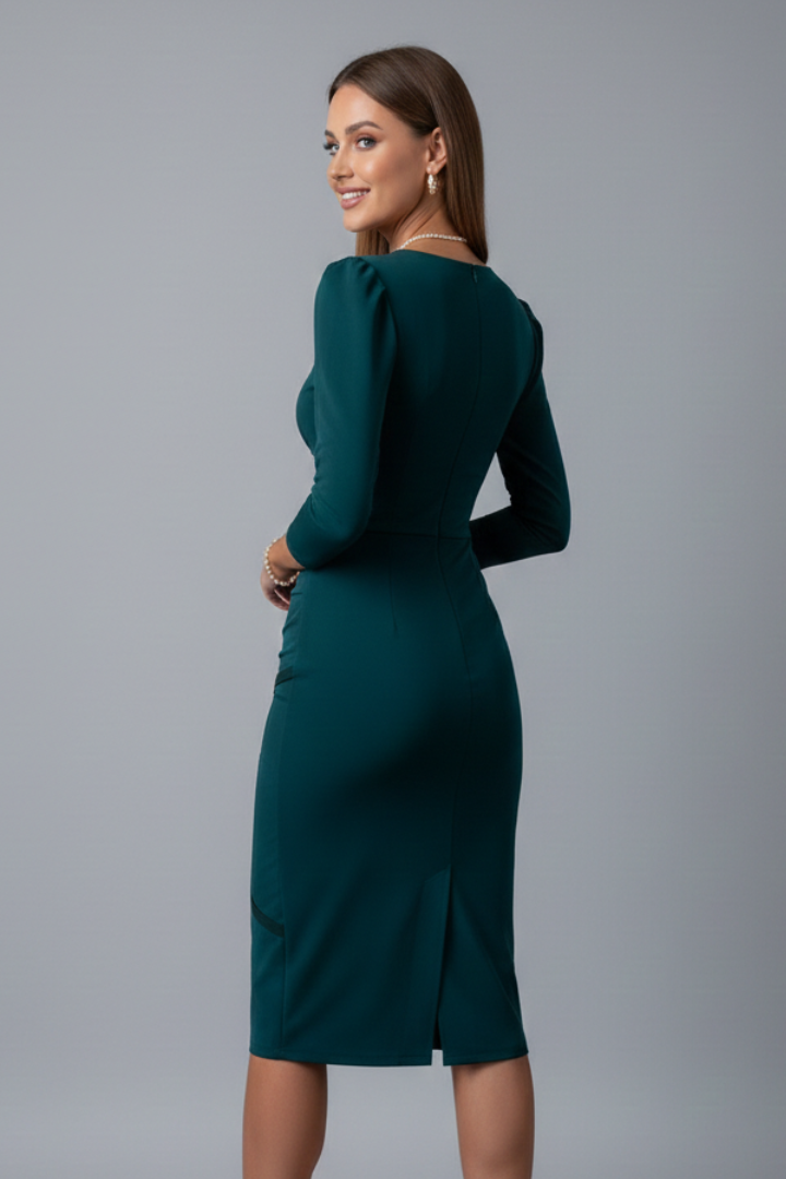 Woman posing sideways in sleek long sleeve dress, plain gray background.