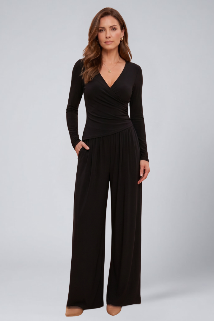 Female model posing in a short sleeve wrap top with matching pants on a plain background.