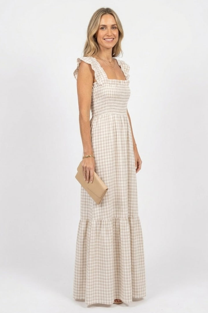 Female model posing in plaid maxi dress on plain gray background.