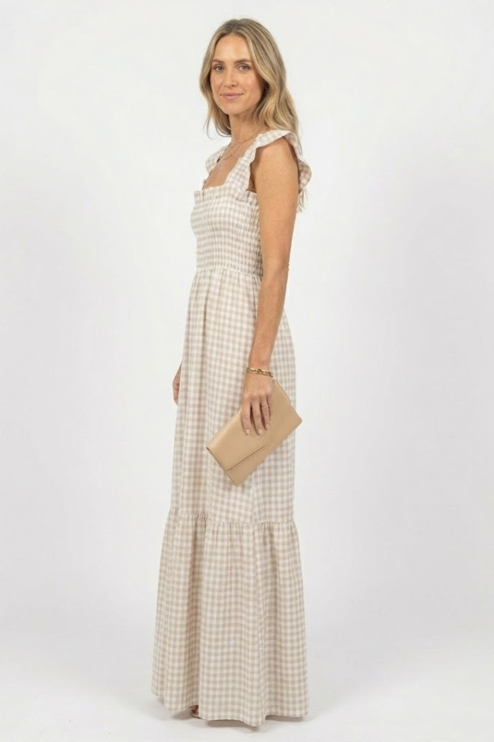 Woman showing full length plaid dress on plain gray background.