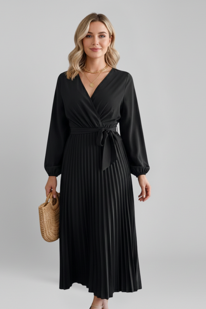 Model in ankle-length pleated black dress, gray studio background