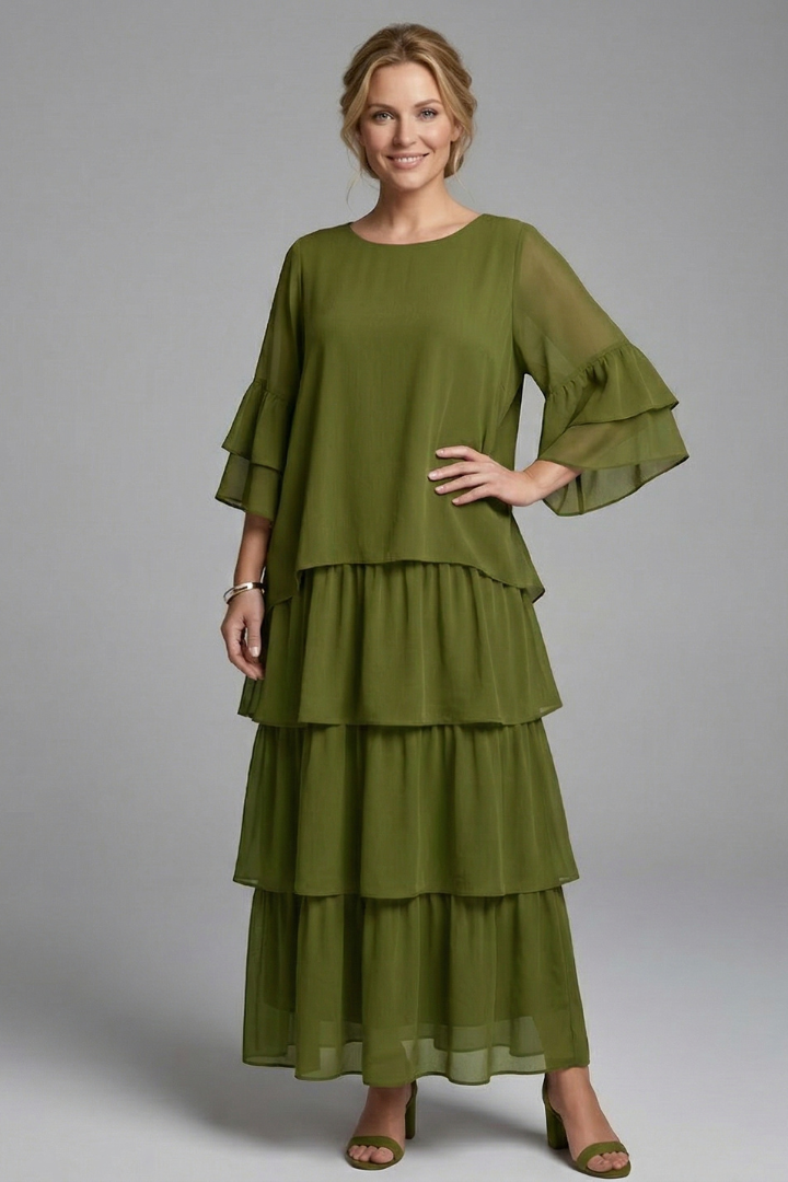 Female model in a relaxed waist maxi dress with flowing tiered skirt on a plain background.