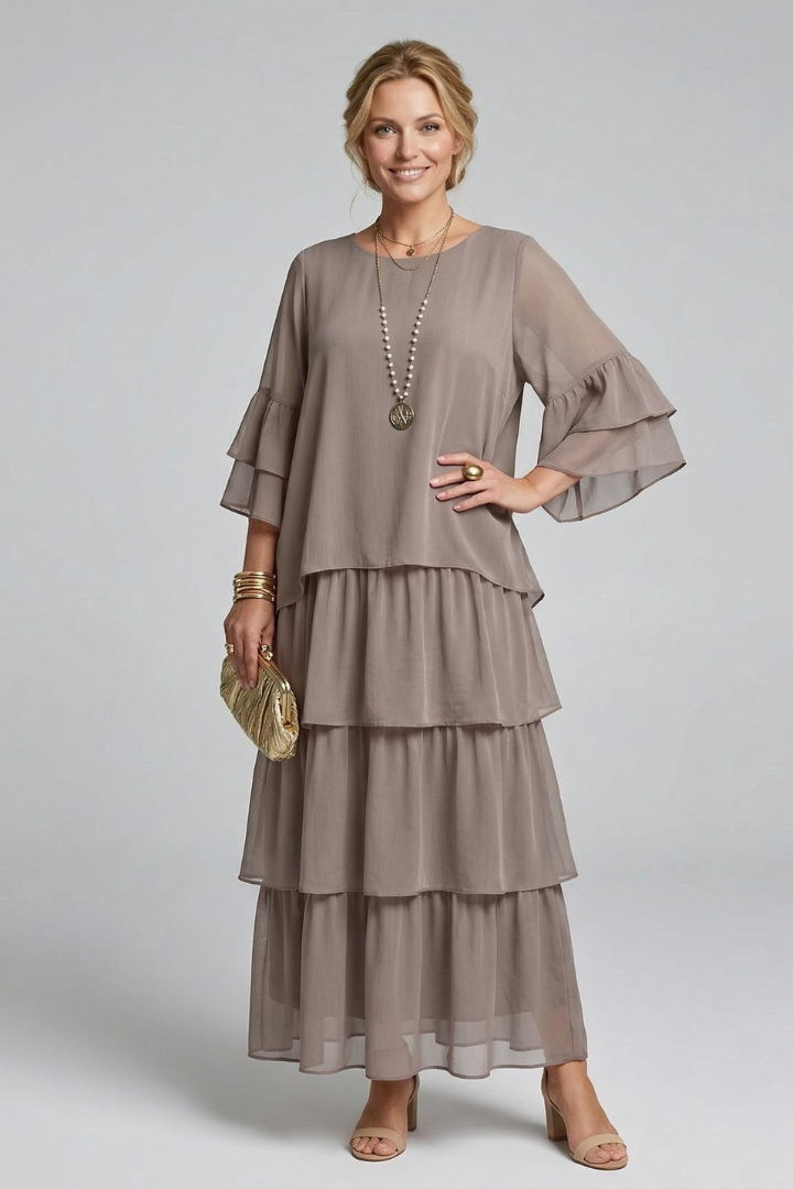 Woman wearing a simple round neck long dress with wide sleeves on a plain background.