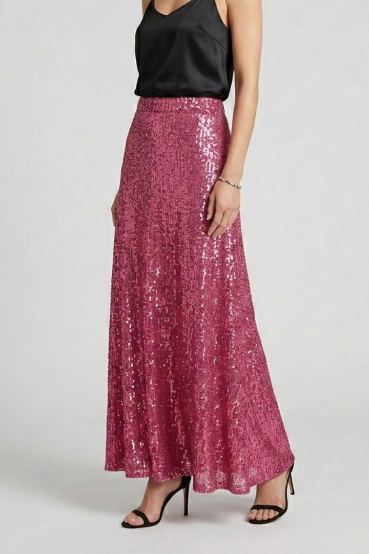Side angle model in shimmer maxi pink skirt with black top and heels