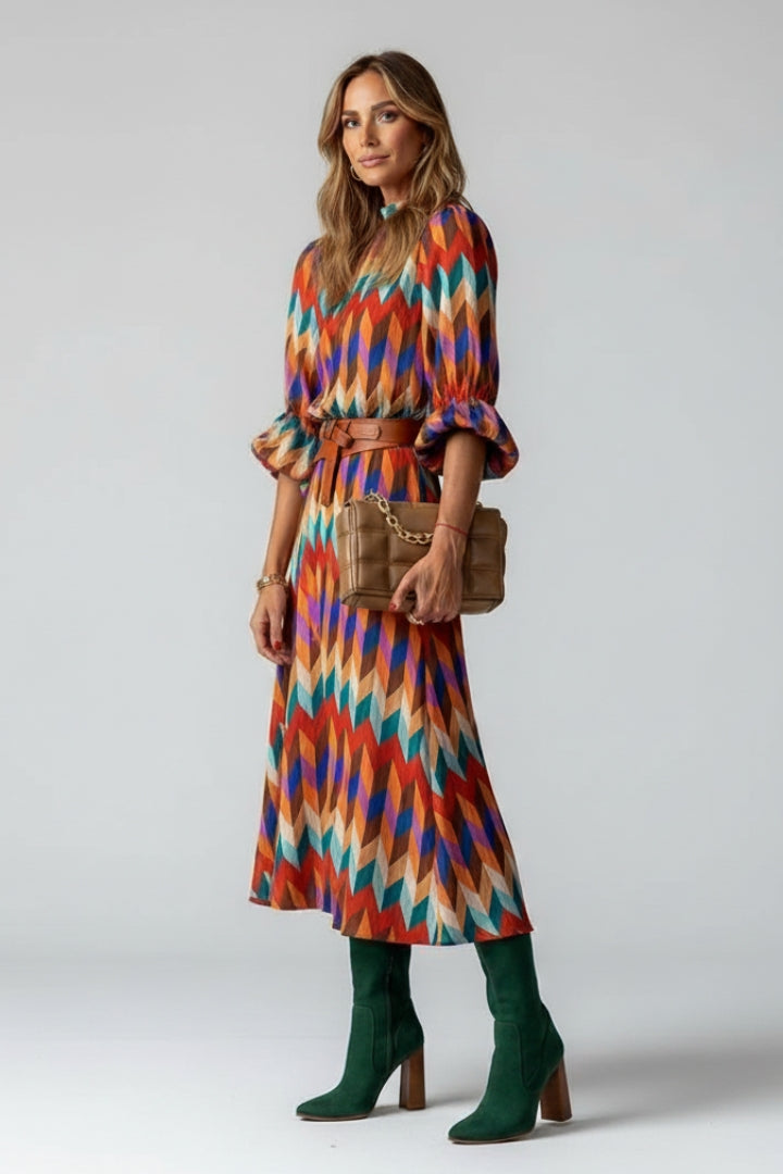 Female model side angle wearing long sleeve printed dress, gray background.