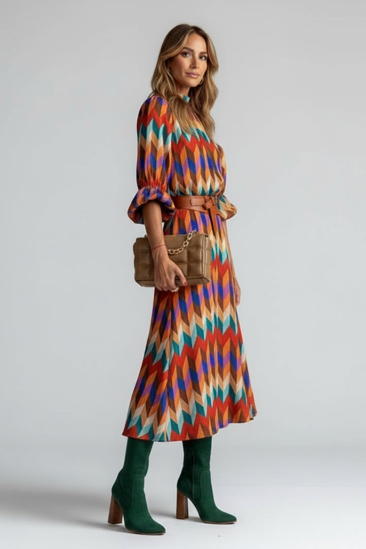 Woman posing front view in patterned midi dress on gray background.