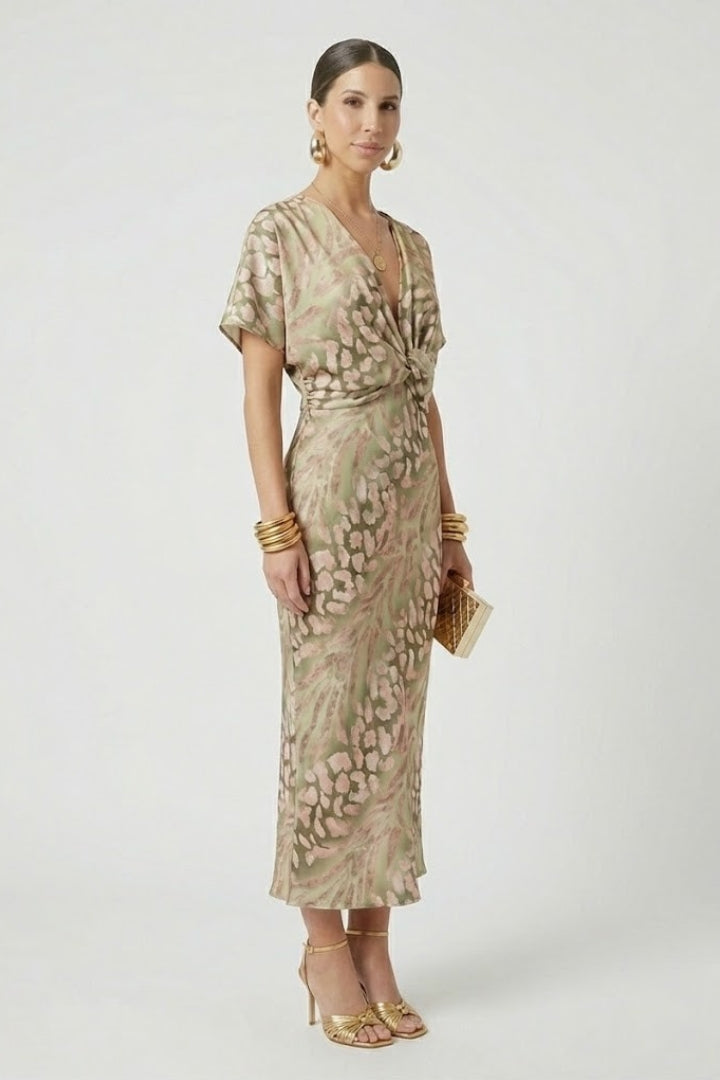 Female model in a V-neck floral midi dress with short sleeves on a plain background.