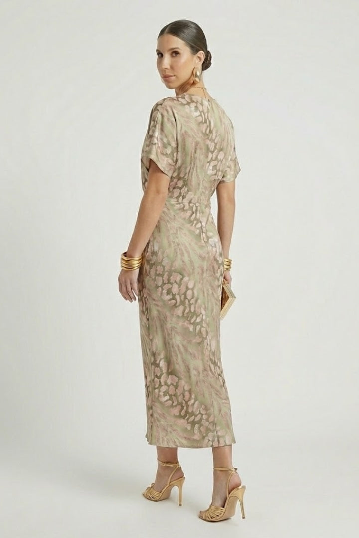 Woman showing a pleated floral dress with defined waist on a plain background.