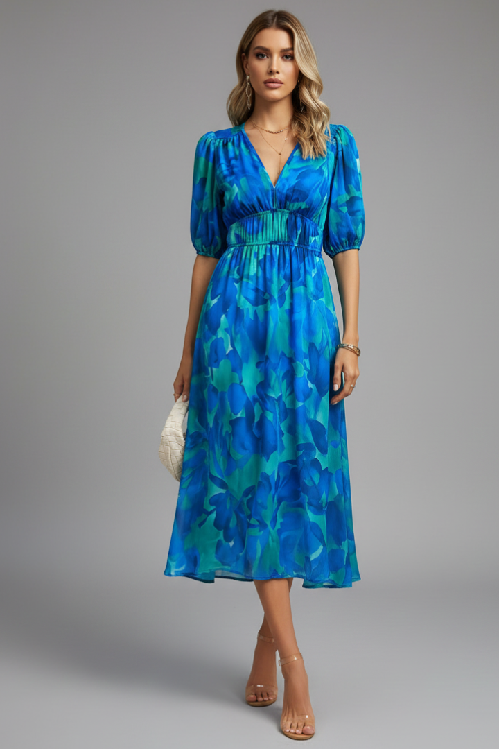 Female model wearing floral midi dress on plain gray background.