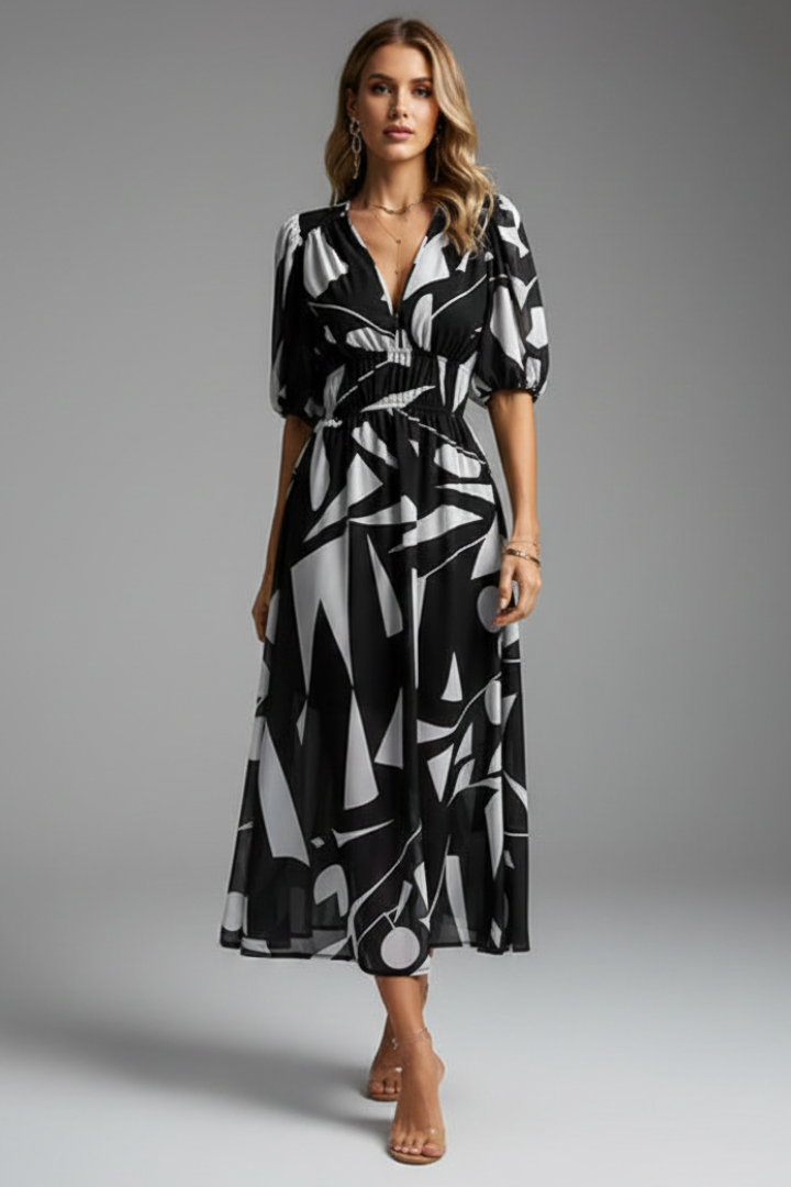 Woman posing in elegant floral dress on gray background.