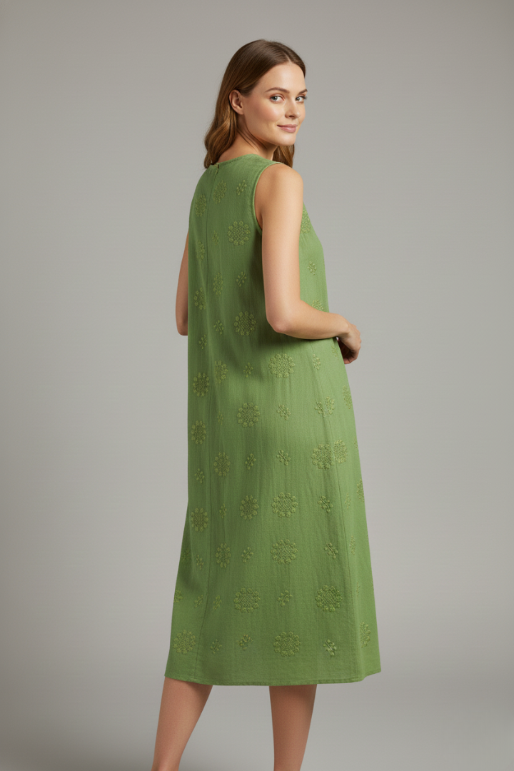 Woman posing sideways in sleeveless textured dress on gray background.