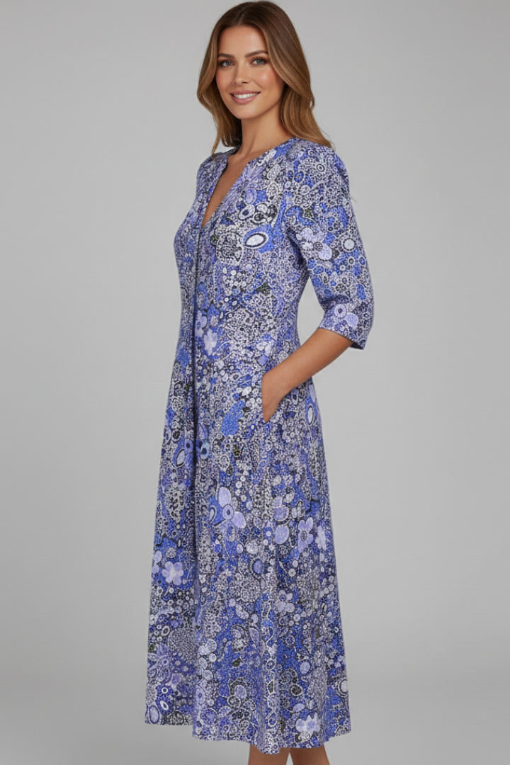Woman in flared printed midi dress standing on plain gray.