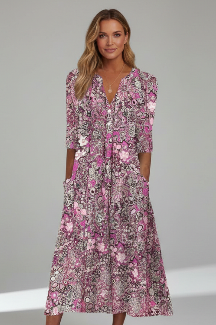 Female model in elegant printed dress facing forward gray backdrop.