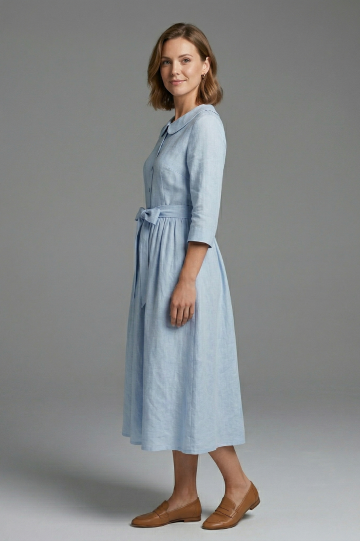 Female model posing in woven midi dress on gray background.