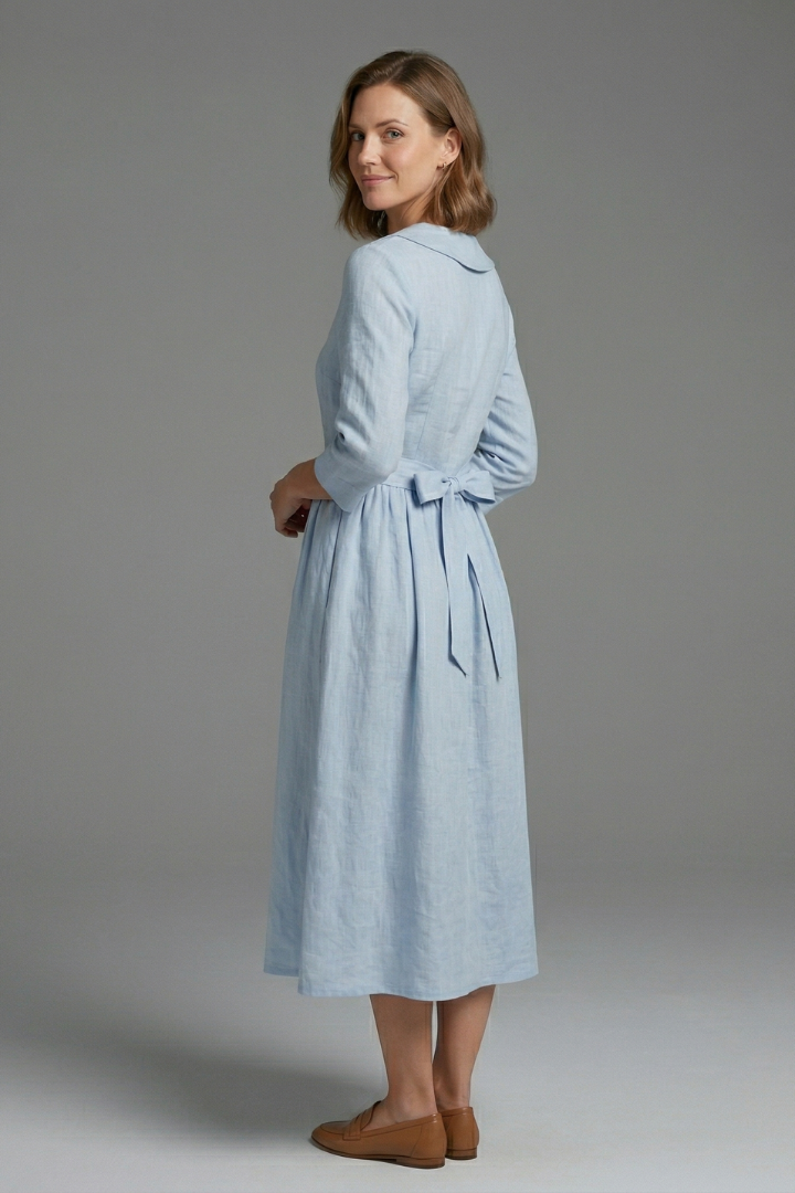 Woman showing side angle of midi dress on gray background.