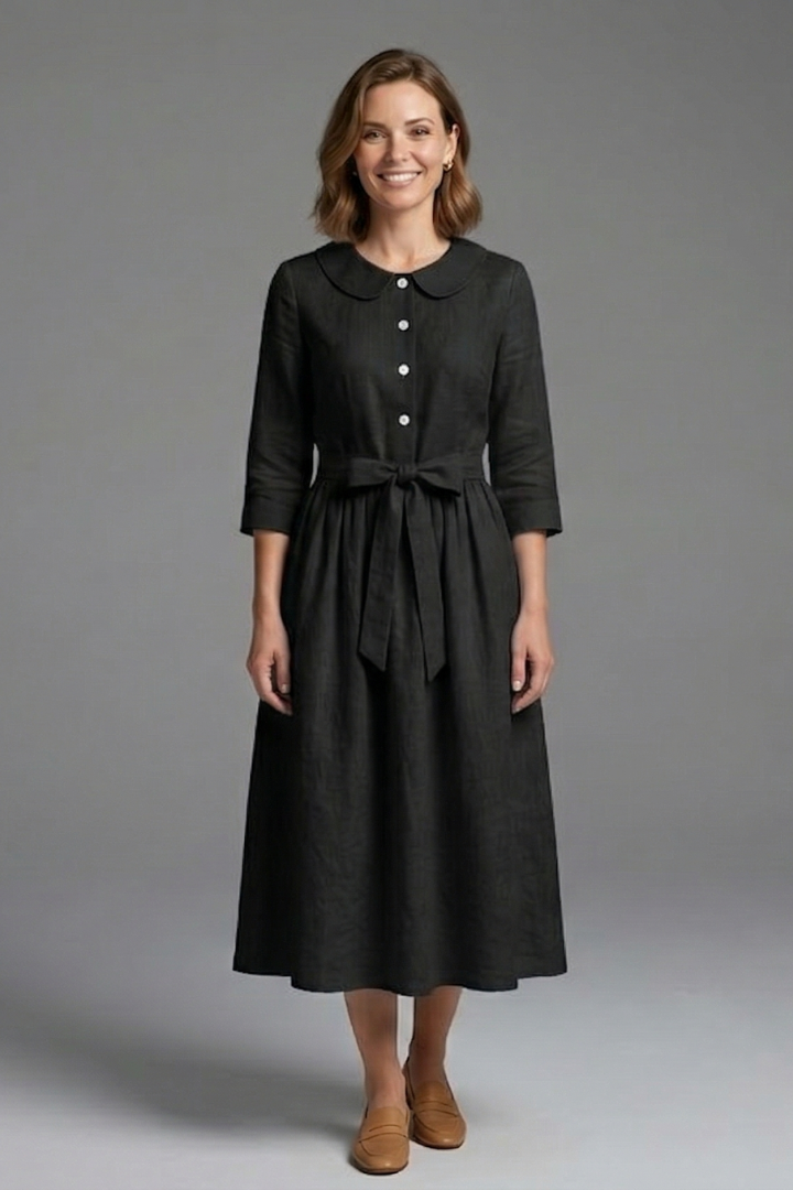 Woman displaying front view of flared midi dress gray background.
