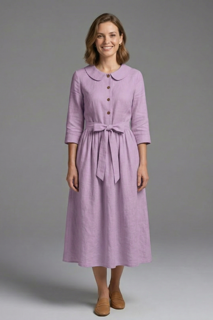 Female model posing with relaxed fit dress gray background.