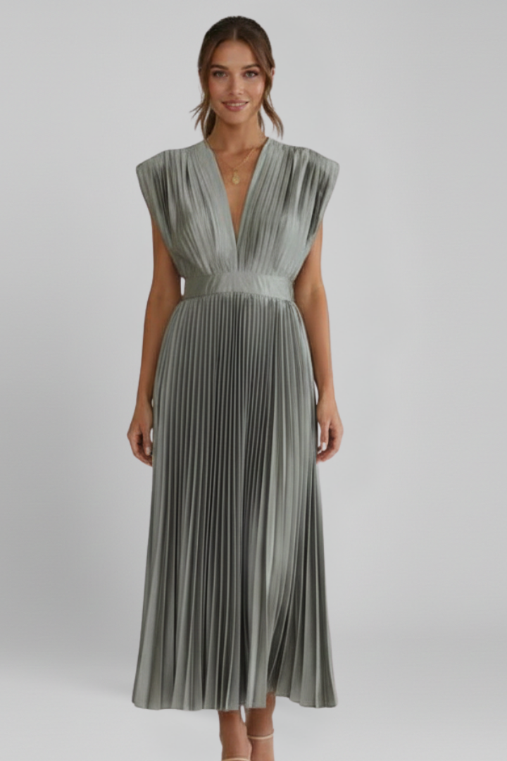 Woman wearing a sleeveless midi dress with a V neckline and pleated skirt on a plain background.