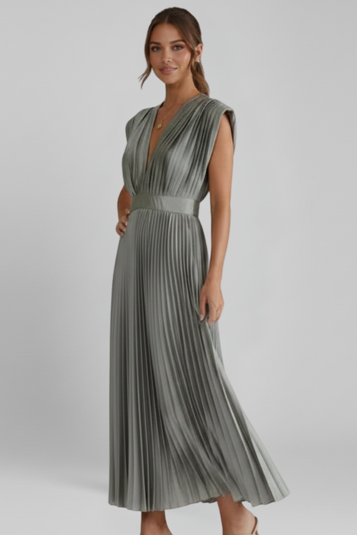 Female model in a sleeveless pleated midi dress with a defined waist on a plain background.